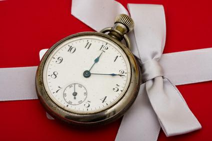 A pocket watch sitting on a red present background, time management